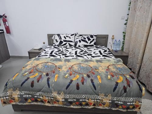 a bed with a black and white comforter with feathers on it at Luxe Studio Prime area near Airport & Attractions in Dubai