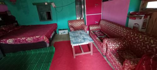 um quarto com duas cadeiras, um sofá e uma cama em Deep Jyoti Home stay em Bāgeshwar