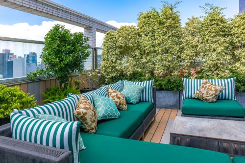 a patio with a green couch with pillows at The Mercer in Hong Kong