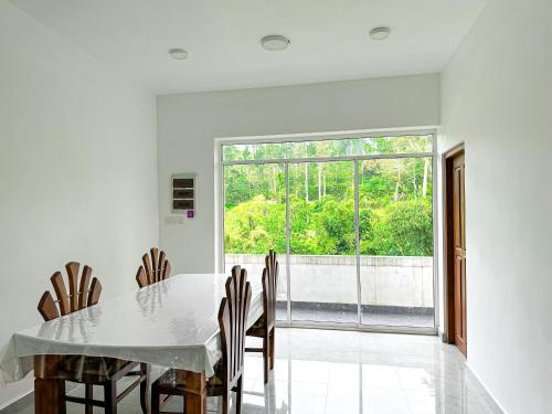 a dining room with a table and chairs and a window at Heaven Hills Guest House in Maskeliya