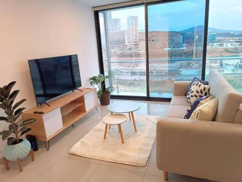 a living room with a couch and a tv and a table at Departamento Linda Vista Privado A/C Cochera 24/7 in Querétaro