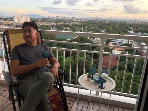 a man sitting in a chair on a balcony with a table at Staycations by SMS in Manila