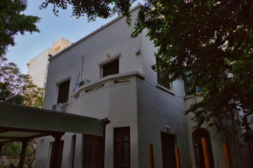 un edificio bianco con un albero di fronte di Egyptus Villa Hostel ad Alessandria d'Egitto