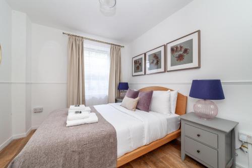 ロンドンにあるSpacious 3BR house wbalcony, South Londonのベッドルーム1室(ベッド1台、ランプ付きテーブル付)