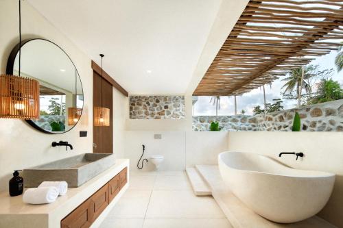 y baño con bañera, lavabo y espejo. en Tias Villas, en Kuta Lombok