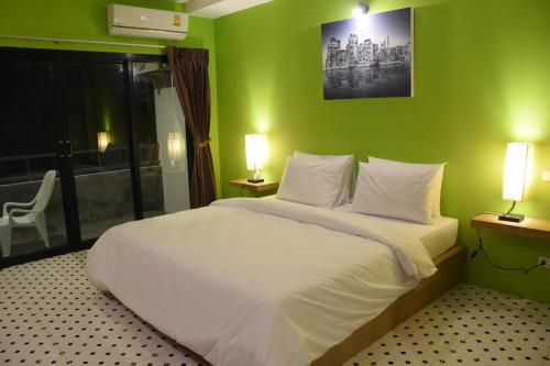 a bedroom with a white bed with a green wall at At Home Khaolak in Khao Lak