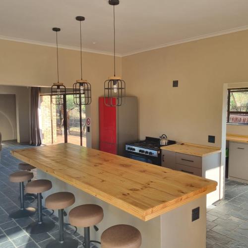 - une cuisine avec une grande table en bois et des tabourets dans l'établissement Makhato Bush Lodge 114, à Bela-Bela