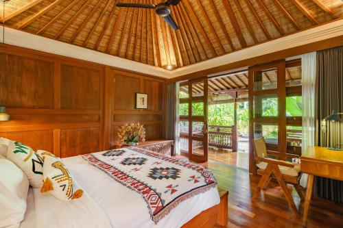 a bedroom with a bed with a ceiling fan and a desk at Villa Asrava Ubud in Ubud
