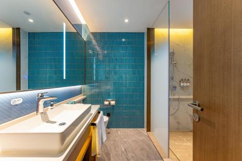 baño con lavabo y ducha con azulejos azules en Holiday Inn Express Suzhou Bay, an IHG Hotel en Suzhou