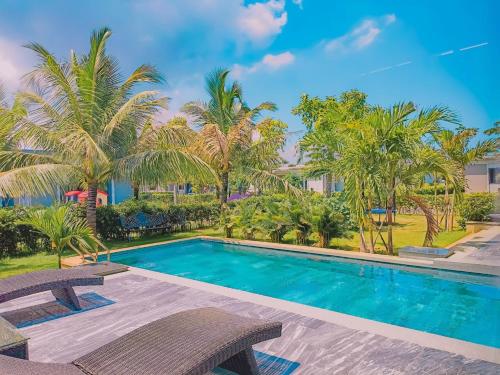 a swimming pool with two chairs and palm trees at 12_LUXURY VILLA COASTAR HỒ TRÀM RESORT ll Private pool ll large garden ll BBQ next to the HAMPTONS 300m - beautifull beach in Xuyên Mộc