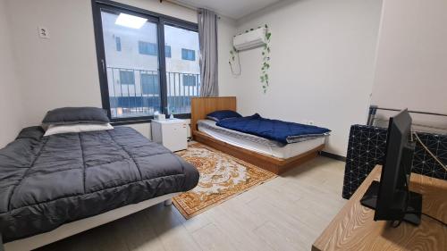 a bedroom with two beds and a flat screen tv at Yolo House in Incheon