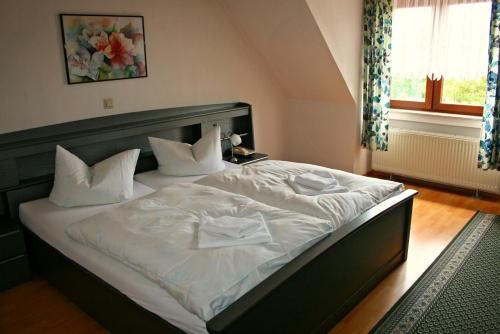 ein Schlafzimmer mit einem großen Bett mit weißer Bettwäsche und Kissen in der Unterkunft GROBER's Reiterhof in Naumburg