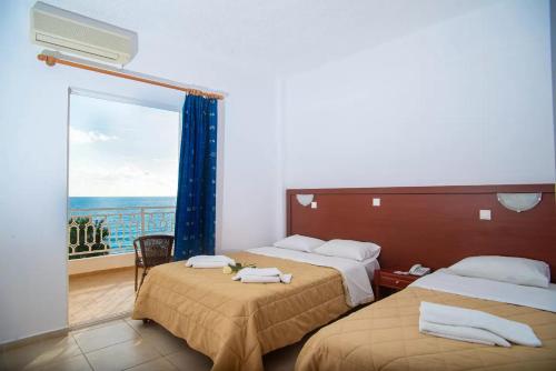 a hotel room with two beds and a balcony at Poseidon Beach Hotel in Kastrosikia