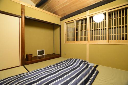 1 dormitorio con cama de rayas azul y blanco en 北房まちの駅 ゲストハウス, en Shimo-azae