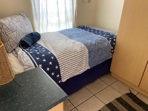 a small bedroom with a bed with an american flag blanket at Sunset Sands in Jeffreys Bay