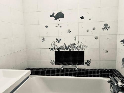 y baño con bañera y pegatinas de pescado en la pared. en Bel appartement, centre culturel, en Vallauris