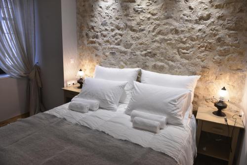 a bed with white pillows and a stone wall at Roptro in Doliana