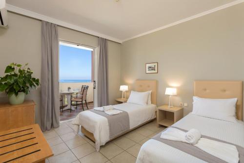 a hotel room with two beds and a table with a view at Xenos Kamara Beach in Argasi