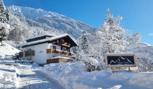 un bâtiment recouvert de neige avec un panneau devant lui dans l'établissement Haus Tisch, à Schruns