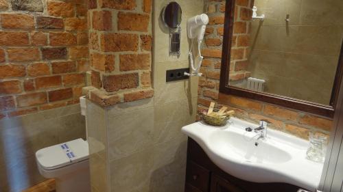 a bathroom with a white sink and a brick wall at Hotel Puerto Rico in Llanes
