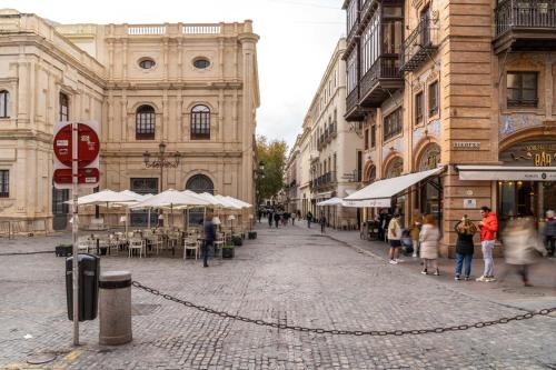 a group of people walking down a street with umbrellas at Limehome Sevilla Calle Granada in Seville