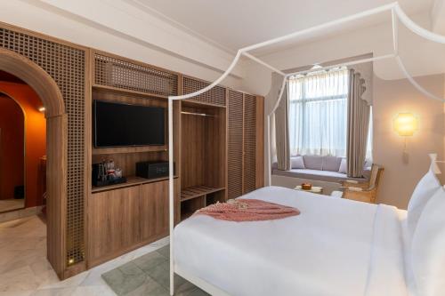 a bedroom with a white bed and a television at Manuscript - Jhilwara Haveli in Udaipur
