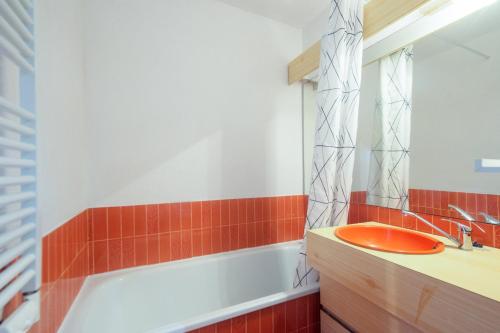 La salle de bains est pourvue d'un lavabo orange et d'une baignoire. dans l'établissement Piolit andCo - Studio vue montagne, à Ancelle