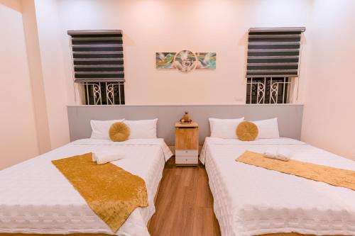 two beds in a room with two windows at Golden Diamond Hotel in Hanoi