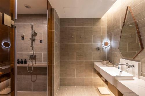 uma casa de banho com um lavatório e um chuveiro em Atour Hotel Zhengzhou Xinzheng International Airport em Zhengzhou