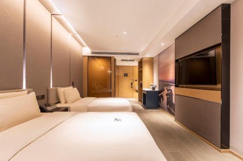 ein Hotelzimmer mit einem Bett und einem Flachbild-TV in der Unterkunft Atour Hotel Zhengzhou Xinzheng International Airport in Zhengzhou