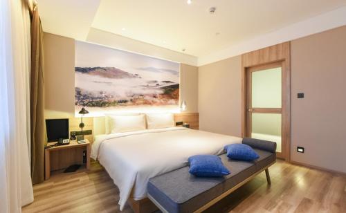 a bedroom with a large white bed with blue pillows at Atour Hotel High Tech Changchun in Changchun