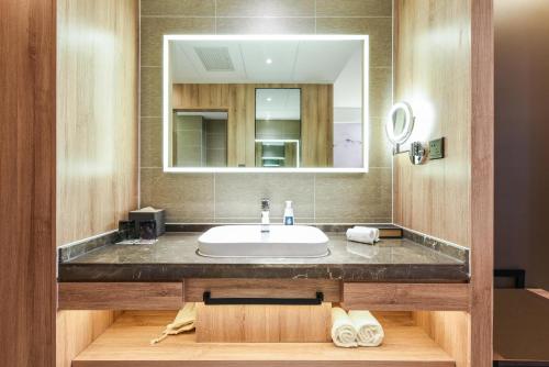 La salle de bains est pourvue d'un lavabo et d'un miroir. dans l'établissement Atour Hotel High Tech Changchun, à Changchun