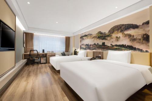 重慶市にあるAtour Hotel Chongqing Jiefangbeiのベッド3台とテレビが備わるホテルルームです。