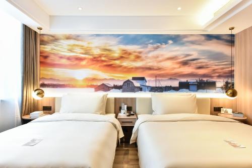 two beds in a hotel room with a sunset at Atour Light Hotel Shenyang Tiexi Plaza Wanxianghui in Shenyang