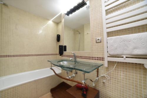 La salle de bains est pourvue d'un lavabo en verre et d'une baignoire. dans l'établissement Encantador Atico cerca de Caldea HUT 6793, à Escaldes-Engordany