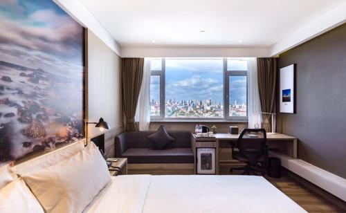 a hotel room with a bed and a desk and a window at Atour Hotel Weihai City Center in Weihai