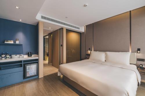 a bedroom with a large white bed and a kitchen at Atour Hotel Huzhou Dongwu in Huzhou