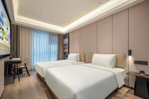 a hotel room with two beds and a flat screen tv at Atour Hotel Shanghai Hongqiao Xinzhuang Business District in Shanghai