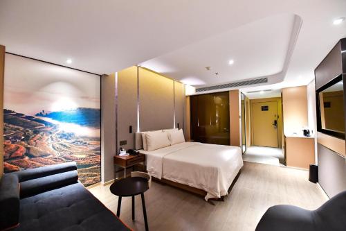 銀川市にあるAtour Hotel Yinchuan Gulou Pedestrian Streetのベッドとソファ付きのホテルルーム