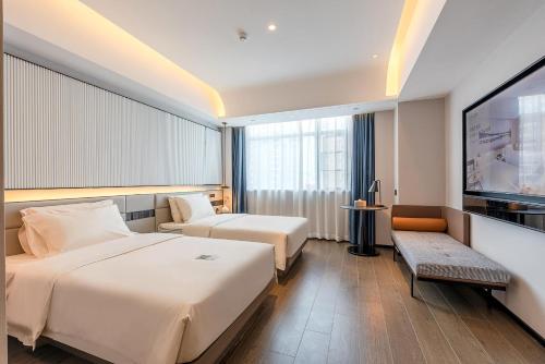 a hotel room with two beds and a flat screen tv at Atour S Hotel Shenzhen Futian Port in Shenzhen
