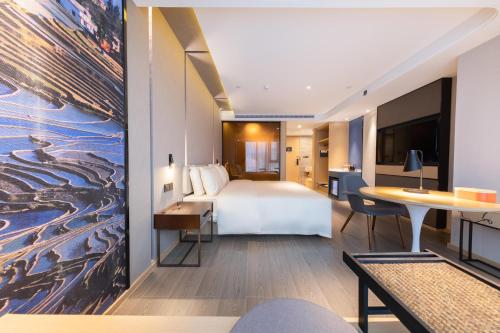 昆明市にあるAtour Hotel Kunming Hi-tech Wuyue Plazaのベッドとデスクが備わるホテルルームです。