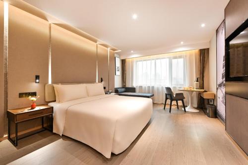 a hotel room with a large white bed and a desk at Atour S Hotel Beijing Anzhen in Beijing