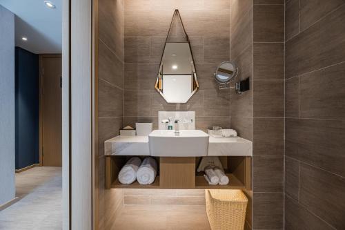 W łazience znajduje się umywalka i lustro. w obiekcie Atour Hotel Hangzhou Xiaoshan Airport w mieście Xiaoshan
