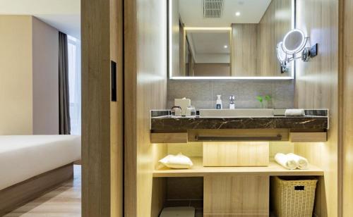 een badkamer met een wastafel en een spiegel bij Atour Hotel Xiamen Huandao South Road in Xiamen