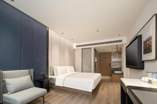 a bedroom with a bed and a tv and a couch at Atour Hotel Fuzhou Jinshan Aegean Sea in Fuzhou