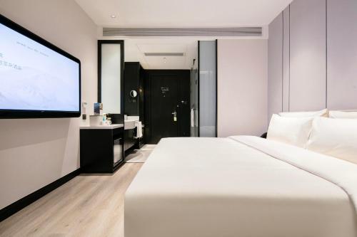 um quarto de hotel com uma grande cama branca e um ecrã de projecção em Atour X Hotel Hangzhou West Lake Wulin Plaza Yan'an Road em Hangzhou