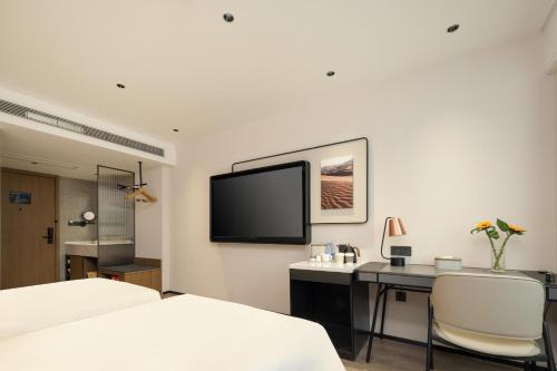 a bedroom with a bed and a desk and a tv at Atour Hotel Fuzhou Jinshan Aegean Sea in Fuzhou