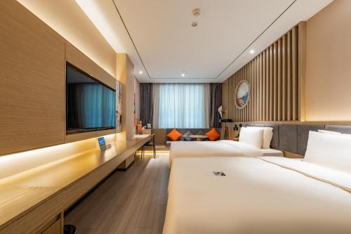 a hotel room with two beds and a flat screen tv at Atour X Hotel Beijing Sanyuan Bridge in Beijing