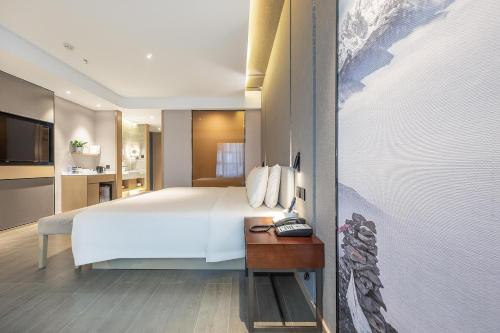 Un dormitorio con una gran cama blanca y una mesa en Atour Hotel Chengdu Wenshufang en Chengdú