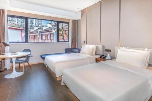 a hotel room with two beds and a table at Atour Hotel Huangshan Tunxi Old Street Xin an River in Huangshan City